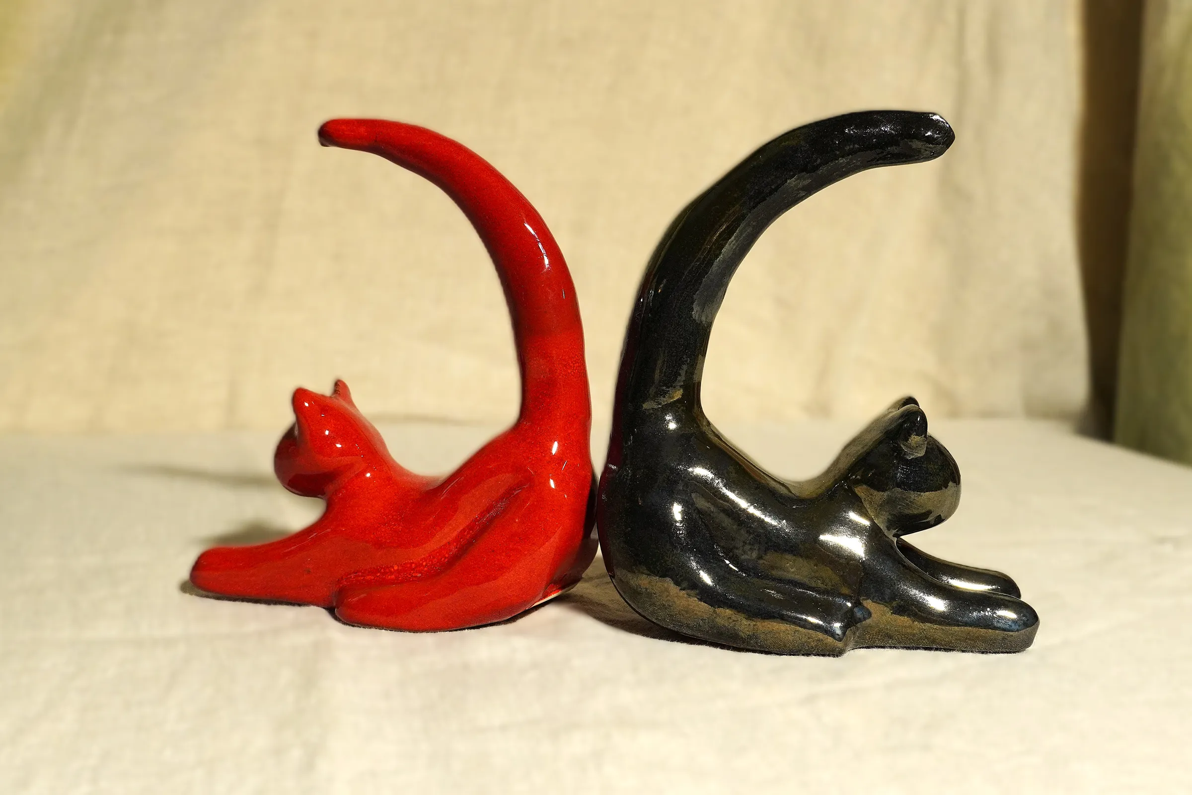 2 chats en céramique, l'un rouge, l'autre noir, se tournant le dos