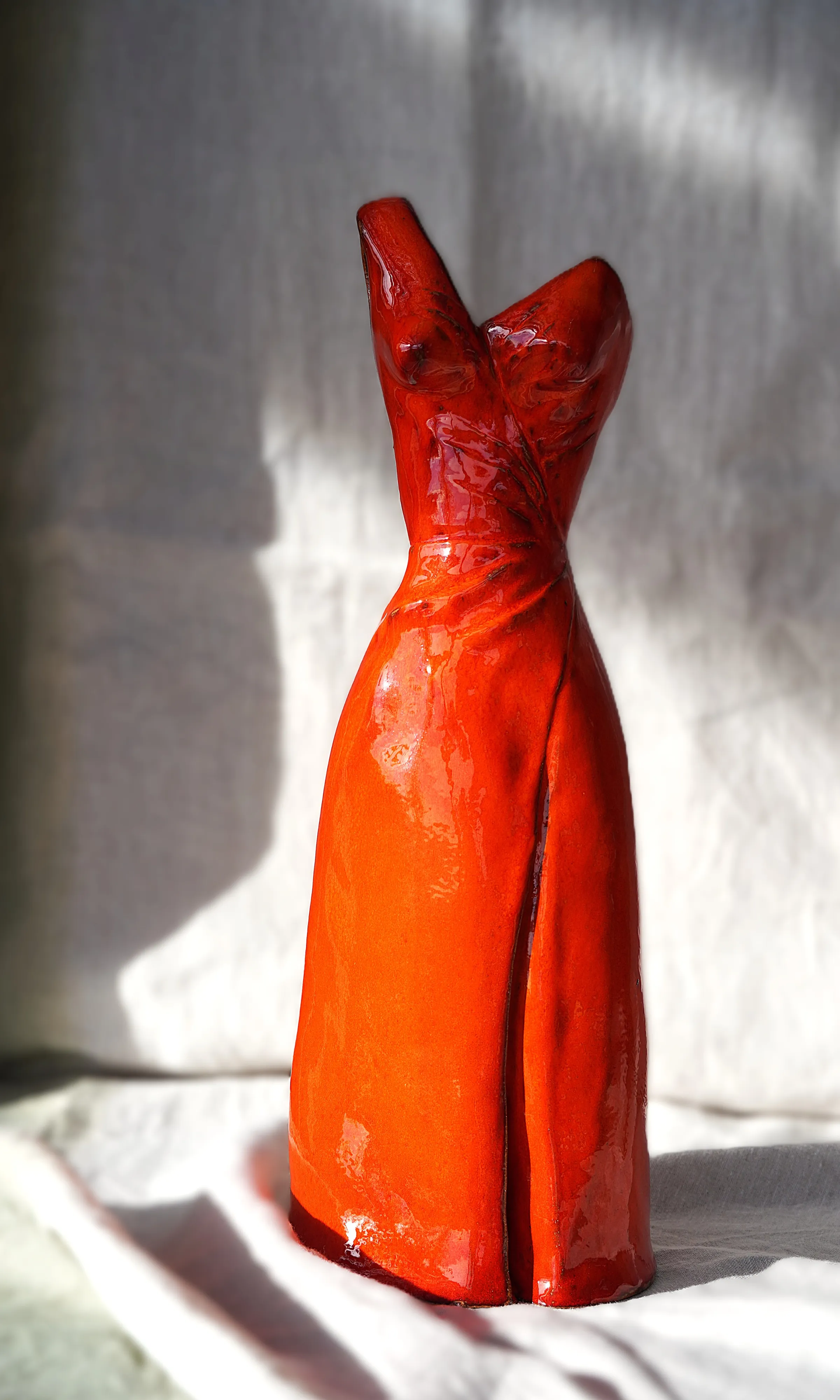 Vase en céramique rouge-orangé en forme de robe avec des courbes féminines