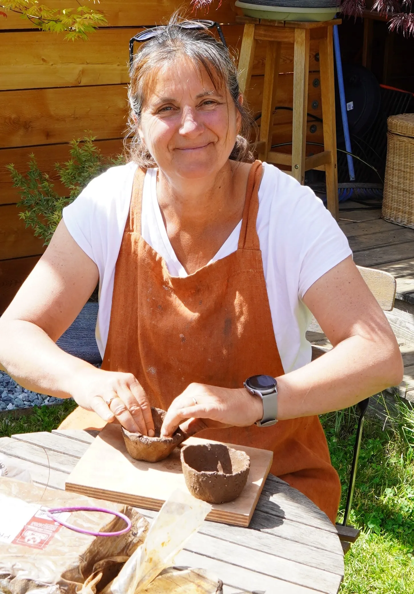 Christine en train de modeler une poterie sur sa table de jardin